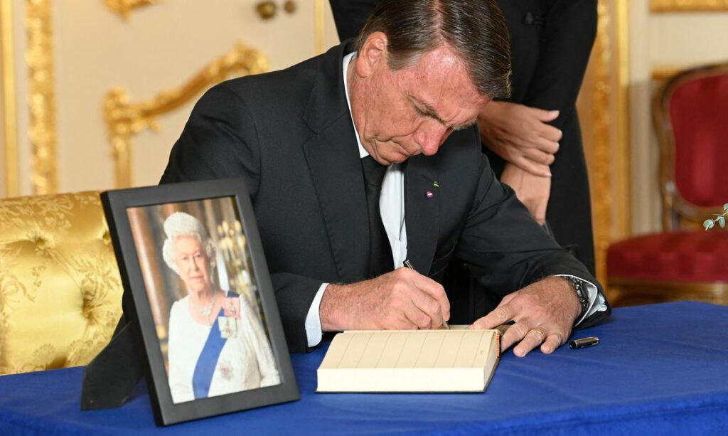 Bolsonaro assinando livro da rainha